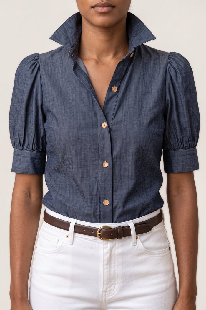 Close-up of the Chambray Puff Sleeve Top showing the tall stand-up collar, the button placket with matte tan buttons and a gathered puff sleeve with its band cuff