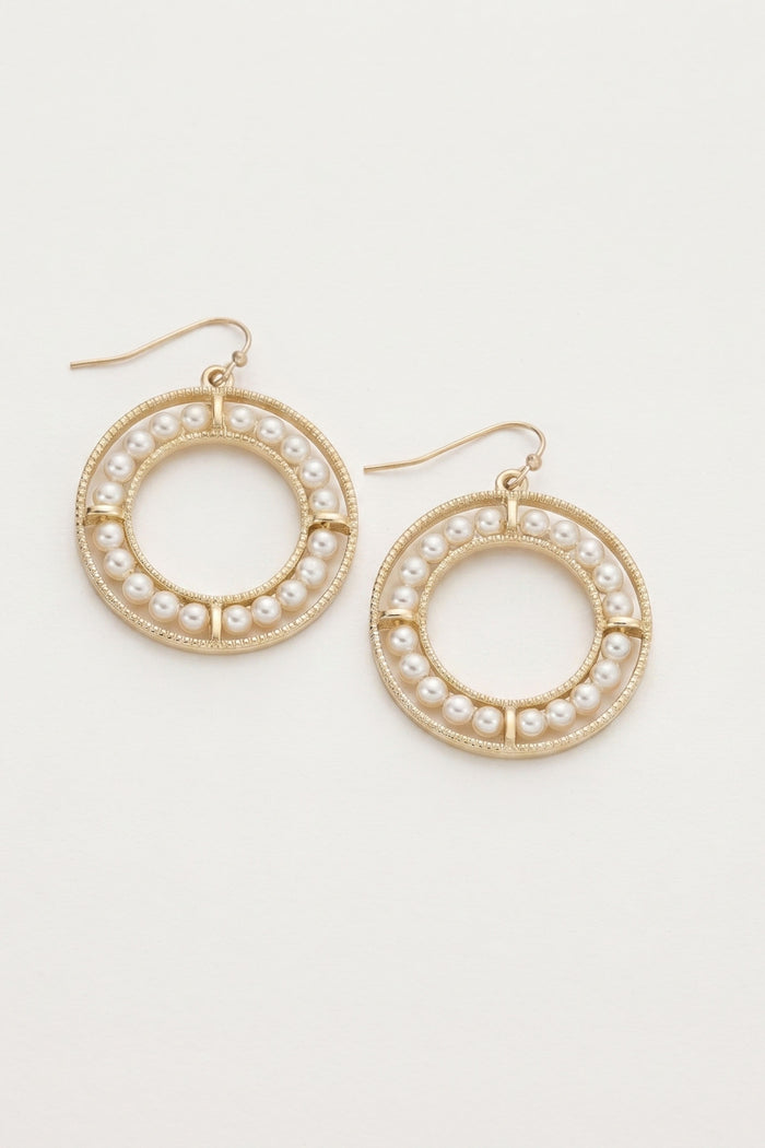 A pair of gold-tone hoop earrings decorated with small white faux pearls, shown on a plain off-white background.
