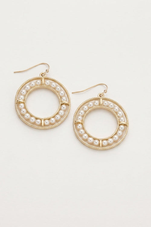 A pair of gold-tone hoop earrings decorated with small white faux pearls, shown on a plain off-white background.