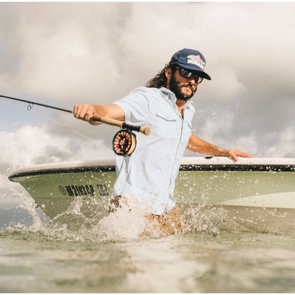 Man wearing Howler Bros light blue UPF 35 fishing shirt while fly fishing